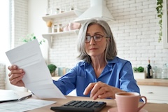 A woman sits at a table calculating taxes on 401(k) withdrawal